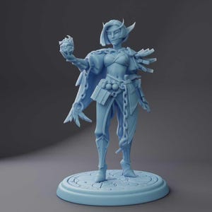 May include: A light blue figurine of a female fantasy character, holding a detailed orb. The figure is adorned with armor, a cape, and chain accents. It stands on a circular base with engraved details, showcasing a detailed design.
