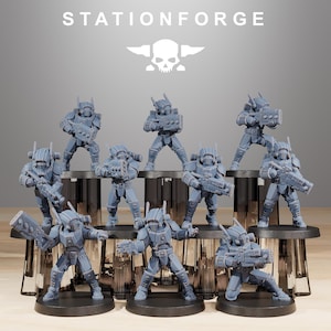 May include: A collection of gray miniature figurines of futuristic soldiers, each armed with a weapon. The figures are arranged on a tiered display stand. The text "STATIONFORGE" is displayed above the figures.