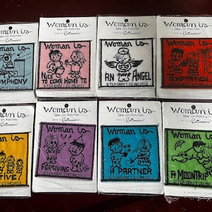 Op de afbeelding: Negen kleurrijke strijklabels met verschillende illustraties en tekst. De labels tonen een verscheidenheid aan thema's, waaronder muziek, huis, engelen, verleiding, creativiteit, vergeving, partnerschap en een maantrip. Elk label heeft de tekst "Woman is" en "Sew-on Patches" erop gedrukt.