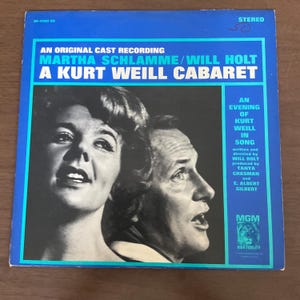 Peut inclure: Une pochette d'album vinyle vintage avec un fond bleu. La couverture présente une image en noir et blanc de deux personnes, Martha Schlamme et Will Holt. Le titre de l'album est "A Kurt Weill Cabaret."