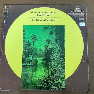 May include: Vintage vinyl record album cover for "Music of Delius, Album 2 Florida Suite" by Sir Thomas Beecham. The cover features a green and black illustration of a river scene with a boat, framed by a large yellow circle.