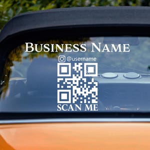 May include: White vinyl decal with the text "BUSINESS NAME" and a QR code with the text "SCAN ME" below it. The decal is on the back window of a yellow car.