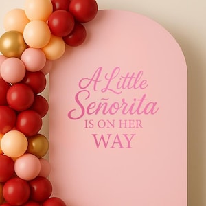 Pode incluir: Uma placa rosa em forma de arco com o texto "A Little Señorita Is On Her Way" em script rosa. Uma guirlanda de balões em tons de vermelho, rosa, dourado e pêssego adorna o lado esquerdo. Um círculo cinza na parte inferior esquerda diz "vinyl decal only".