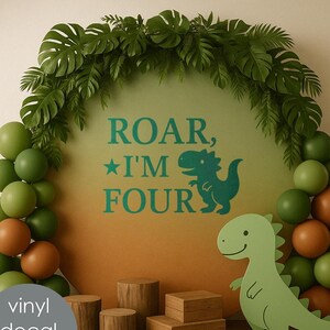 Może przedstawiać: Zielona naklejka winylowa z dinozaurem z tekstem "Roar, I'm Four" na zielonym i pomarańczowym tle. Naklejka jest otoczona zielonymi i brązowymi balonami oraz drewnianymi klockami.