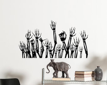 May include: A black wall decal featuring numerous skeleton hands reaching upwards. The hands are depicted in various positions. Below, a decorative elephant statue with a crown is displayed on a shelf.
