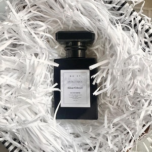 May include: A black square bottle of perfume with a black cap. The label reads "No. 37 Estietiql Bibliotheque Eau de Parfum The Art and Science of Flowers and Elegant Essences 100 ml".