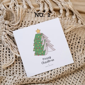 May include: A white Christmas card with a cartoon Christmas tree design. The tree is made of green book pages, decorated with red and yellow lights, and topped with a yellow star. The card reads "Merry Christmas & Happy New Year".