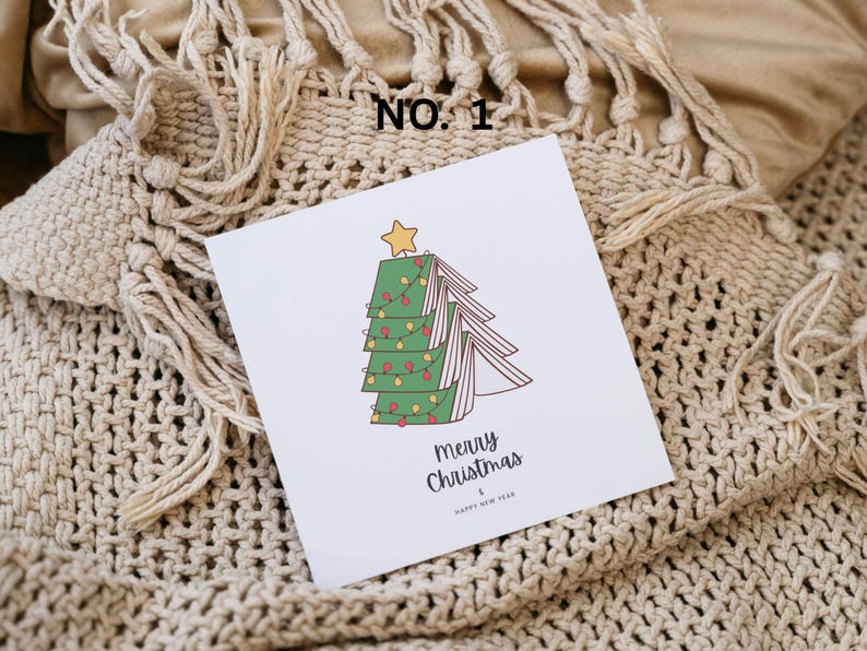 May include: A white Christmas card with a cartoon Christmas tree design. The tree is made of green book pages, decorated with red and yellow lights, and topped with a yellow star. The card reads "Merry Christmas & Happy New Year".