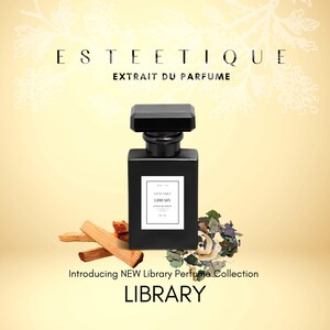 May include: A black perfume bottle with a square shape and a black cap. The bottle has a white label with text. The image includes the text "ESTETIQUE EXTRAIT DU PARFUME" and "Introducing NEW Library Perfume Collection LIBRARY".