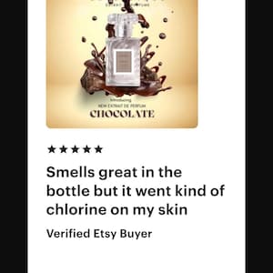 May include: A perfume bottle with a clear glass body and a clear cap, set against a backdrop of chocolate-colored liquid and splashes. The label reads "CHOCOLATE" and "NEW EXTRAIT DE PERFUM".