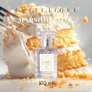 May include: A perfume bottle with a clear, rectangular design and a clear, faceted cap. The label reads "Marshmallow Cake" and "100 ml." The bottle is set against a backdrop of a slice of cake with white frosting and yellow cake.