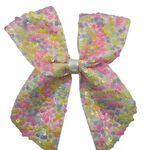 May include: A large white bow with iridescent sequins in shades of pink, yellow, and purple.