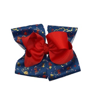 May include: A large hair bow featuring a vibrant red bow atop a navy blue base. The navy blue fabric is patterned with gold and red decorative elements. This accessory is suitable for various occasions.