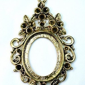 Peut inclure: Pendentif de cadre photo ovale en métal doré avec des détails floraux ornés et une bordure décorative. Le cadre a une boucle en haut pour l'accrocher.