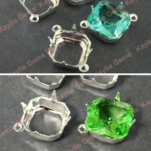 May include: Two silver-toned metal settings for square-shaped gemstones. One setting is empty, and the other has a light green gemstone in it. The settings have a decorative design around the edges and two loops on the side.