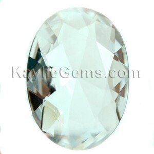May include: A clear, faceted oval-shaped crystal with a slightly bluish tint. The crystal is cut with many facets, giving it a sparkling appearance.