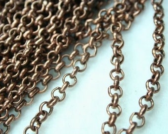 Op de afbeelding: Een close-up van een koperen ketting. De ketting is gemaakt van kleine, ronde schakels. De ketting ligt op een wit oppervlak.