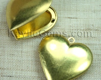 May include: Two gold heart-shaped locket pendants. One locket is open, revealing a smooth interior. The other locket is closed and has a small loop at the top for attaching a chain.