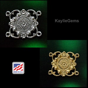 May include: Two ornate metal connector pieces for jewelry making. The piece on the left is silver and the piece on the right is gold. Both pieces have a square shape with a decorative center and four loops.