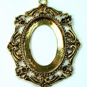 Peut inclure: Cadre ovale en métal doré avec des détails ornés. Le cadre est conçu pour contenir un camée ou un autre petit objet décoratif.