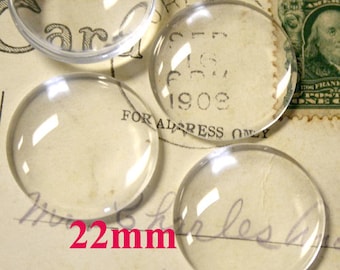 May include: Four clear glass cabochons, each measuring 22 mm in diameter, are arranged on a vintage postcard. The postcard features a stamp with a portrait of a man and the text "United States of America".