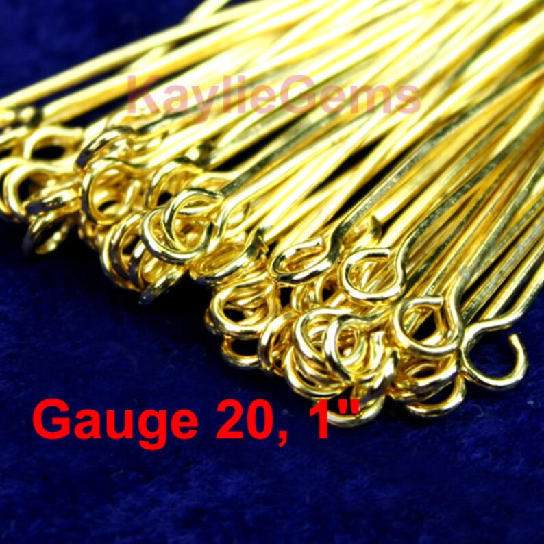 May include: A close-up of a pile of gold-colored, 1-inch long jump rings. The rings are 20 gauge and have a loop on one end. The text "Gauge 20, 1" is visible in the image.