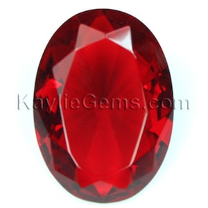 May include: A deep red oval-shaped gemstone with a faceted cut.