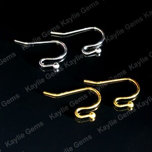 May include: Two pairs of earring hooks, one pair is silver and the other is gold. The hooks are made of metal and have a small ball at the end.