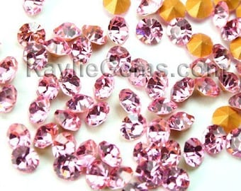 May include: A collection of pink and gold rhinestones. The rhinestones are scattered on a white surface.