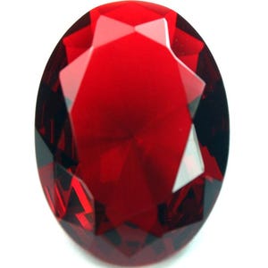 May include: A faceted, oval-shaped gemstone with a deep red hue. The gem's surface reflects light, showcasing its multiple facets and internal structure. The gemstone is set against a white background, highlighting its color and clarity.