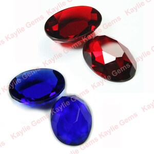 May include: Two sets of oval-shaped faceted glass gems. One set is red and the other is blue.