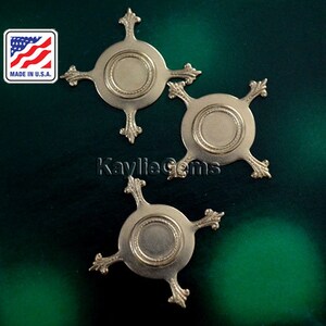 May include: Three gold-toned metal embellishments with a circular design and four points. Each embellishment has a raised, circular center with a decorative border.