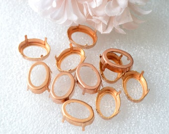 Puede incluir: Un grupo de diez engastes de metal de color cobre de forma ovalada para cabujones. Los engastes tienen cuatro garras a cada lado y están diseñados para sujetar una piedra en su lugar.