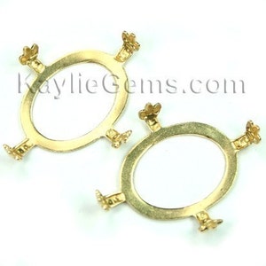 May include: Two gold-tone metal oval-shaped settings with four prongs each. The settings are designed to hold a cabochon stone.