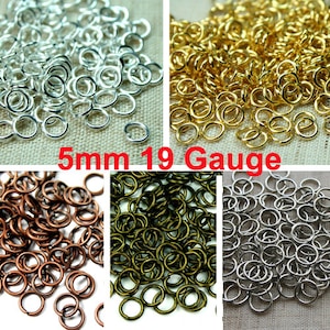 Puede incluir: Una imagen de primer plano de una gran cantidad de anillas de salto de 5 mm en cuatro colores diferentes: plata, oro, bronce y lat&oacute;n antiguo. Las anillas de salto son de calibre 19.