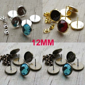 Puede incluir: Surtido de engastes para pendientes de 12 mm en acabados plateado, dorado y bronce. Cada engaste presenta una base redonda con un poste y un cabujón transparente, azul o rojo.