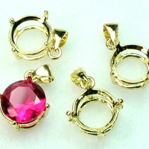 May include: Four gold-tone pendant settings, three are empty and one has a bright pink gemstone.