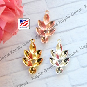 May include: Three gold-toned metal leaf-shaped pendants with a round hole at the top for stringing. The pendants are in different shades of gold, with one being a rose gold color.