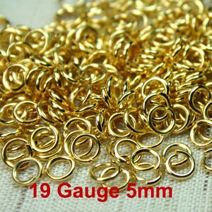 Puede incluir: Una imagen de primer plano de un mont&oacute;n de anillos de salto dorados. Los anillos tienen un di&aacute;metro de 5 mm y un calibre de 19. Los anillos est&aacute;n dispuestos en un patr&oacute;n aleatorio.