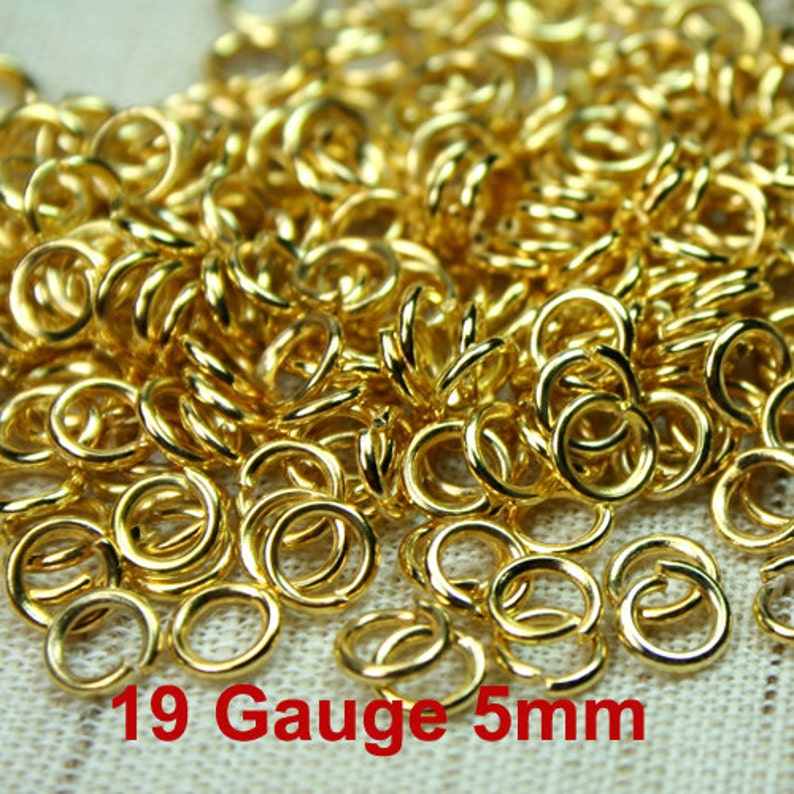Puede incluir: Una imagen de primer plano de un mont&oacute;n de anillos de salto dorados. Los anillos tienen un di&aacute;metro de 5 mm y un calibre de 19. Los anillos est&aacute;n dispuestos en un patr&oacute;n aleatorio.