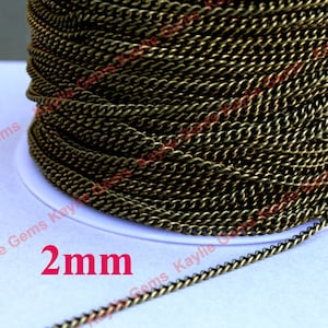 May include: A close-up of a spool of 2 mm thick, gold-toned metal chain. The chain is made of small, linked loops and has a slightly textured finish.