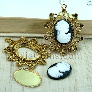 Puede incluir: Tres marcos de camafeo de metal dorado con diseños ornamentados. Un marco presenta un camafeo blanco de un perfil de mujer sobre un fondo negro. Los otros dos marcos están vacíos.