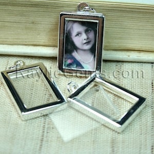 May include: Three silver-toned metal picture frames with a clear glass insert. The frames are rectangular and have a simple design. The largest frame has a photo of a young girl with blonde hair.