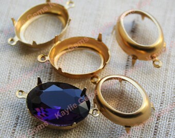Puede incluir: Cuatro engastes ovalados de metal dorado para cabujones, uno de los cuales está lleno de una piedra preciosa púrpura. Los engastes tienen garras para sujetar las piedras en su lugar y bucles para sujetarlas a joyas.