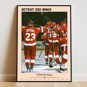 May include: A vintage-style poster featuring a group of hockey players in red and white uniforms celebrating a victory. The poster has the text "DETROIT RED WINGS" at the top and "11 Stanley Cups" below the image. The years 1936, 1937, 1943, 1950, 1952, 1954, 1955, 1997, 1998, 2002, and 2008 are listed below the text.