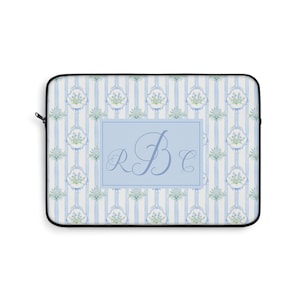 May include: A light blue and white striped laptop sleeve with a floral pattern and the initials "RBC" in a light blue rectangle. The sleeve has a black zipper and trim.