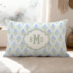 May include: A rectangular throw pillow featuring a repeating blue and green floral damask pattern on a white background. In the center, a light green decorative frame contains the monogram letters BMD in a matching light green serif font.