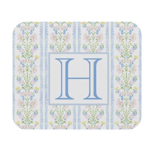 May include: A rectangular mousepad with rounded corners. The design features a floral pattern in pastel colors of pink, blue, and yellow, with a light blue border. A large, light blue letter "H" is centered on a white background.