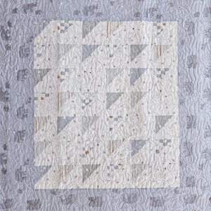 May include: A quilt featuring a central square block pattern composed of alternating white, grey, and striped triangles. The fabric is decorated with a repeating line-art motif of giraffes and swirls, stitched with a continuous quilting pattern.