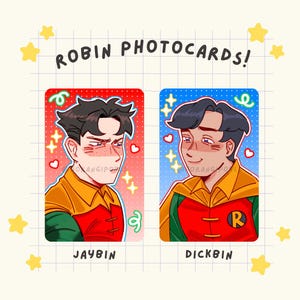 May include: Two Robin photocards with illustrations of characters in red, yellow, and green costumes. The text "ROBIN PHOTOCARDS!" is at the top. One card says "JAYBIN" and the other says "DICKBIN". The background is a grid pattern with yellow stars.